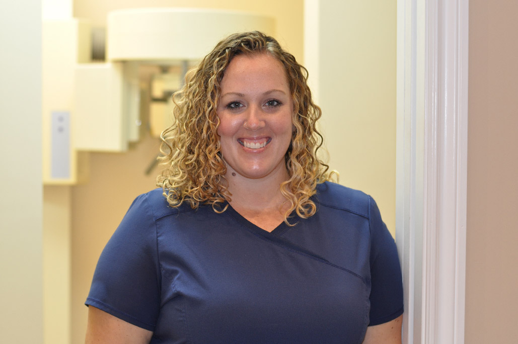 Ashley Varney, dental assistant and receptionist, wearing navy blue scrubs in a doorway at Karen Archer DDS in Leamington, ON