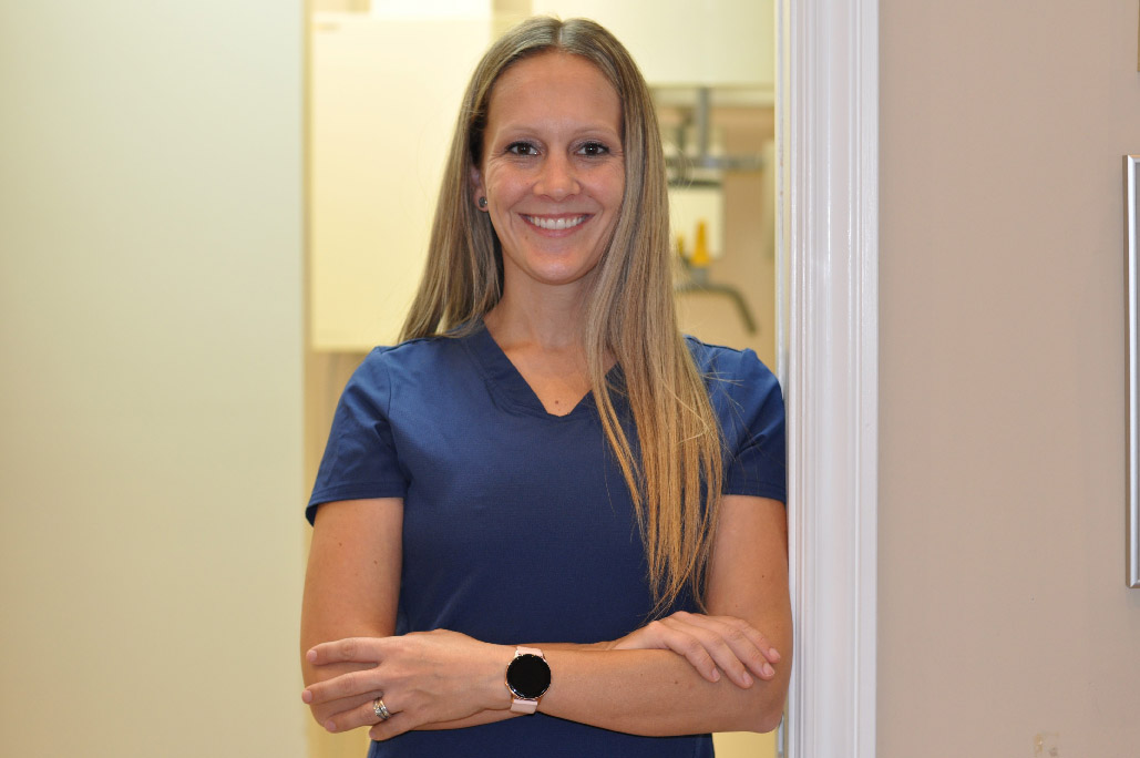 Candace Massad, office manager, arms crossed over her blue scrubs in a doorway at Karen Archer DDS in Leamington, ON